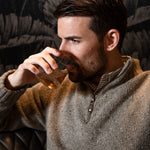Man wearing Cumberland Donegal Sweater and drinking beverage