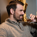 Man wearing Cumberland Donegal Sweater and drinking beverage