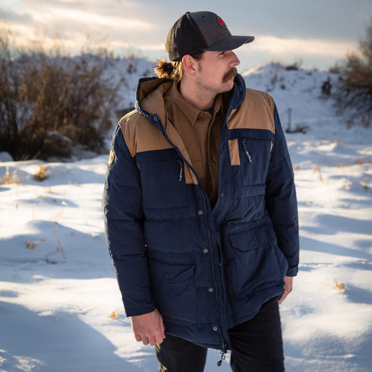 A man wears Pine Peak Down Parka standing in the snow.