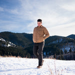 A man wears Pine Peak Down Shirtjac standing in the snow
