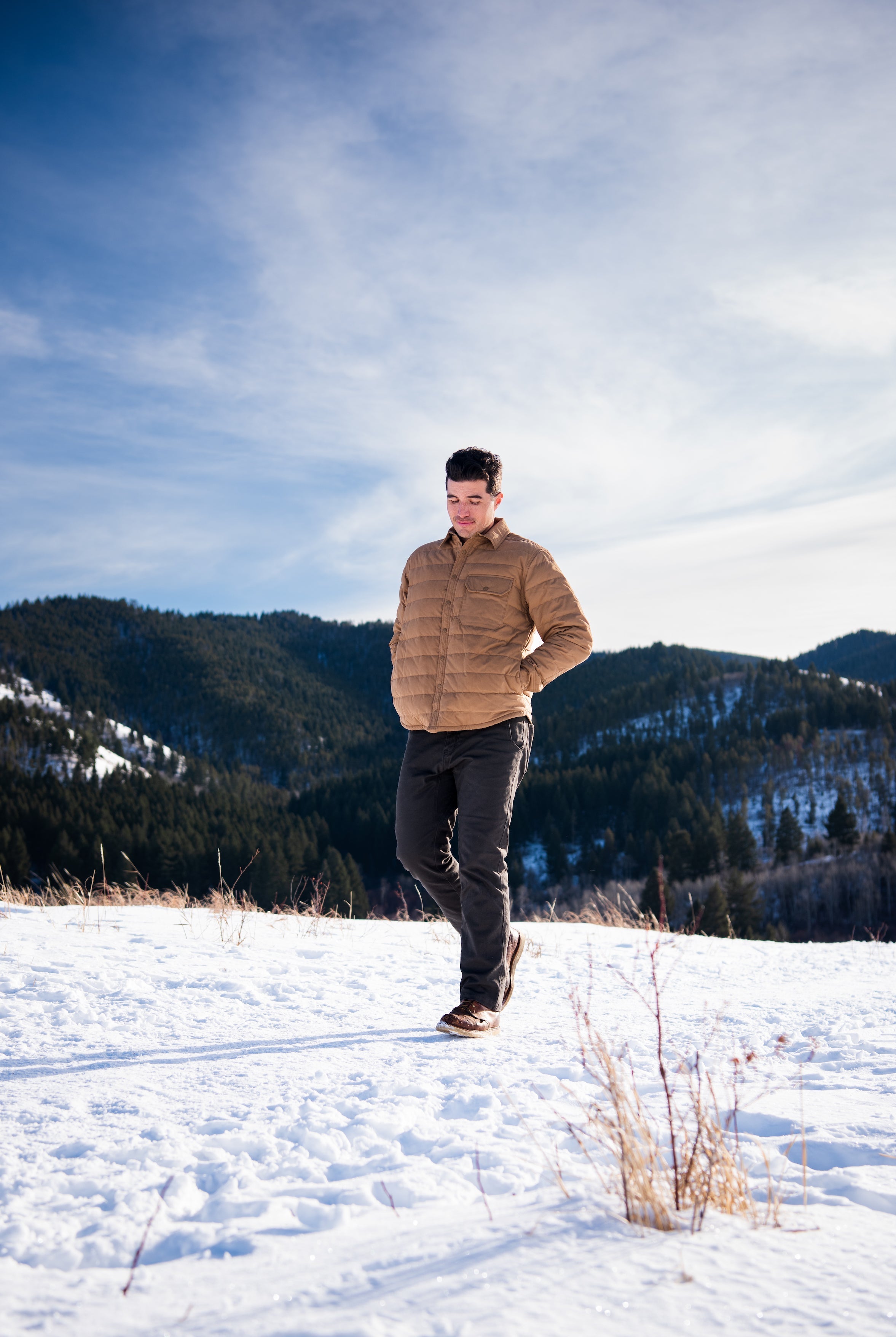 A man wears Pine Peak Down Shirtjac standing in the snow