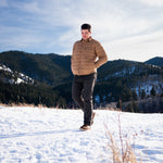 A man wears Pine Peak Down Shirtjac standing in the snow