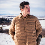 A man wears Pine Peak Down Shirtjac standing in the snow