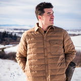 A man wears Pine Peak Down Shirtjac standing in the snow