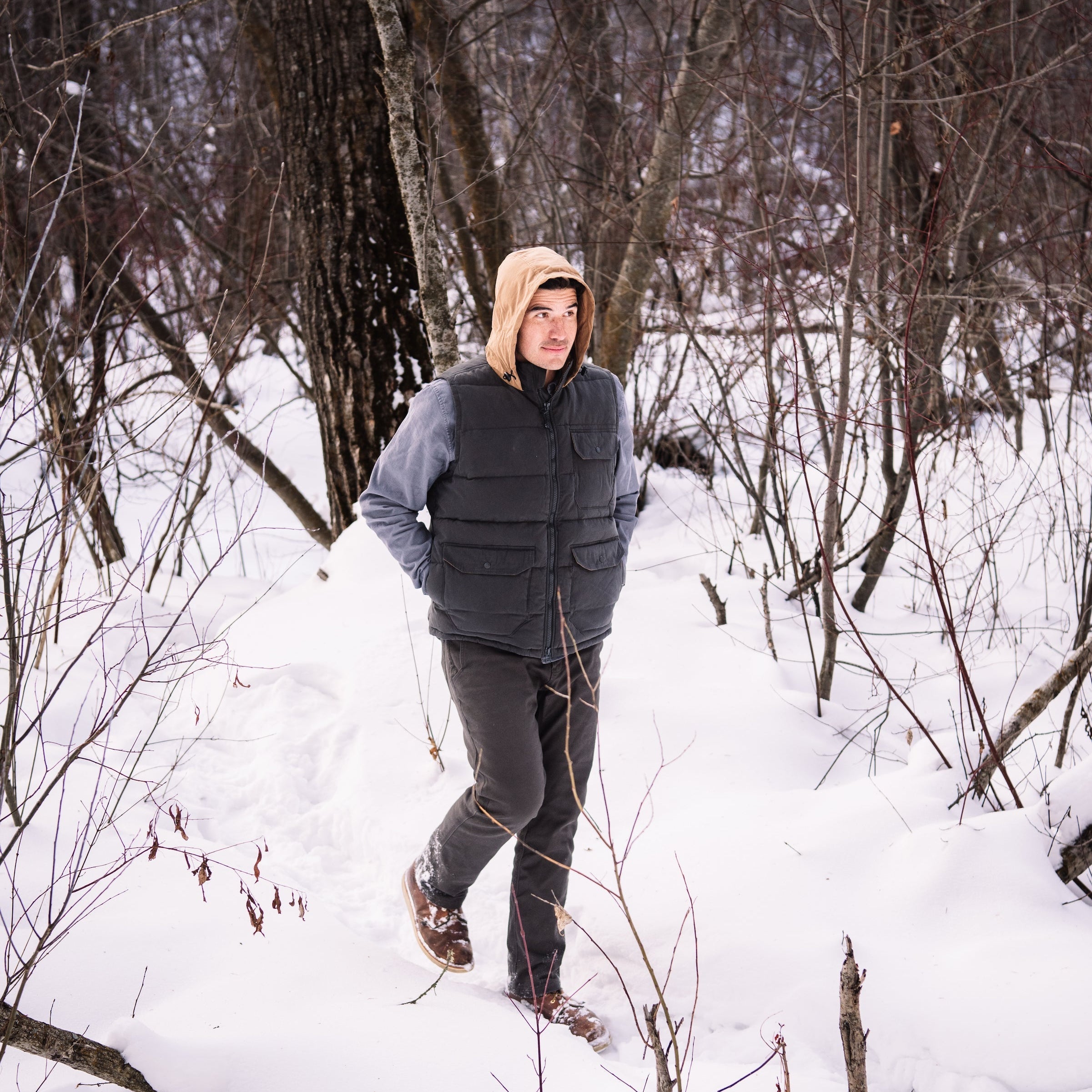 A man wears Pine Peak Down Vest standing in the snow