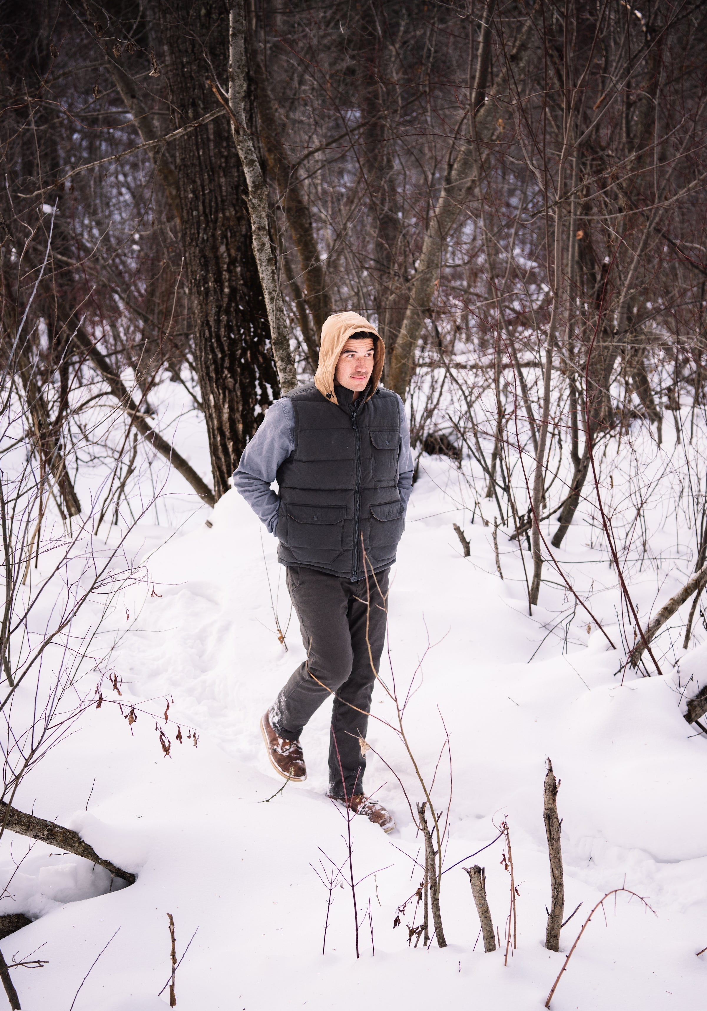 A man wears Pine Peak Down Vest standing in the snow