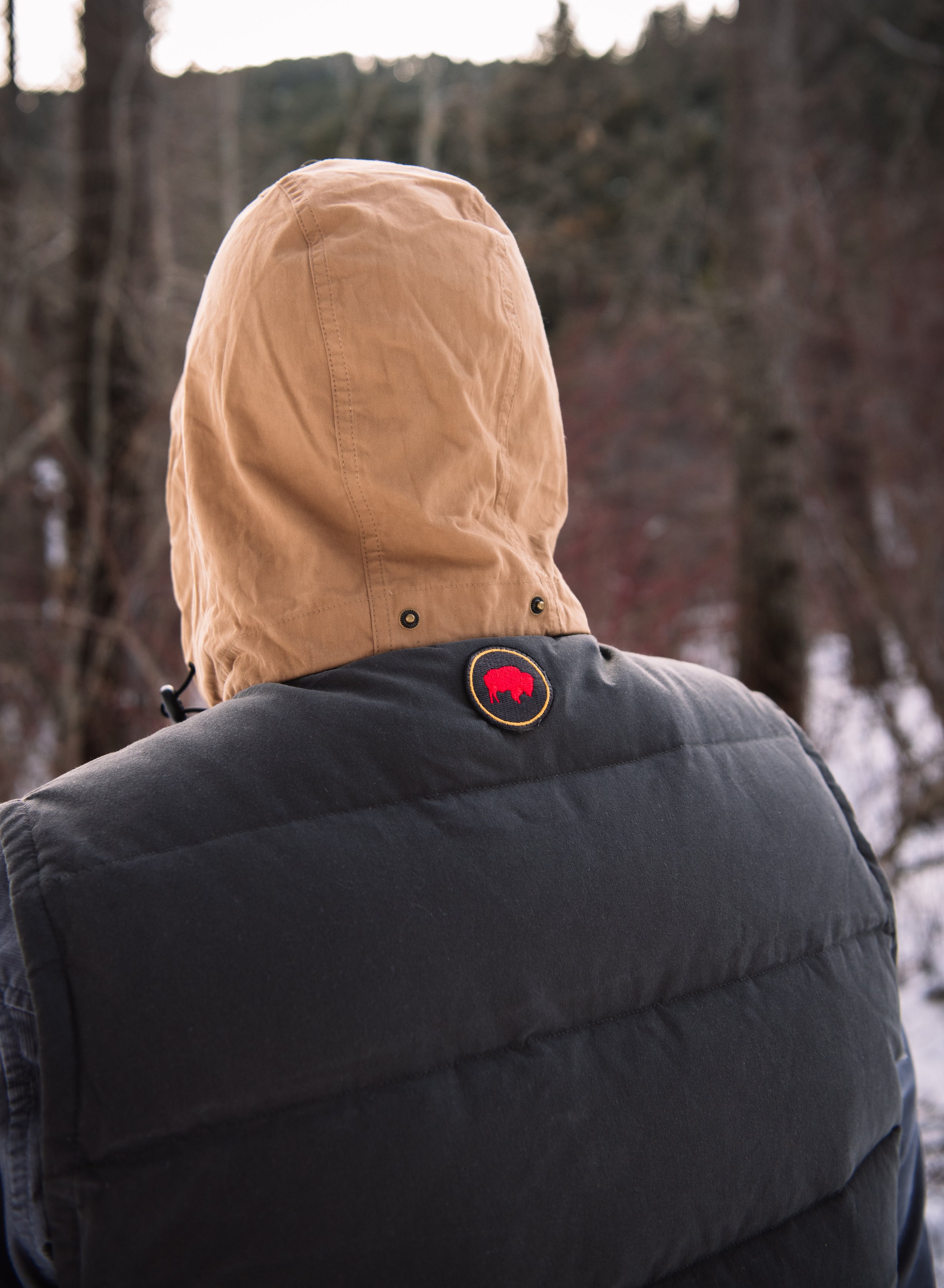 A man wears Pine Peak Down Vest standing in the snow