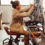 Man wearing Alpine Utility Jacket fixing motocycle