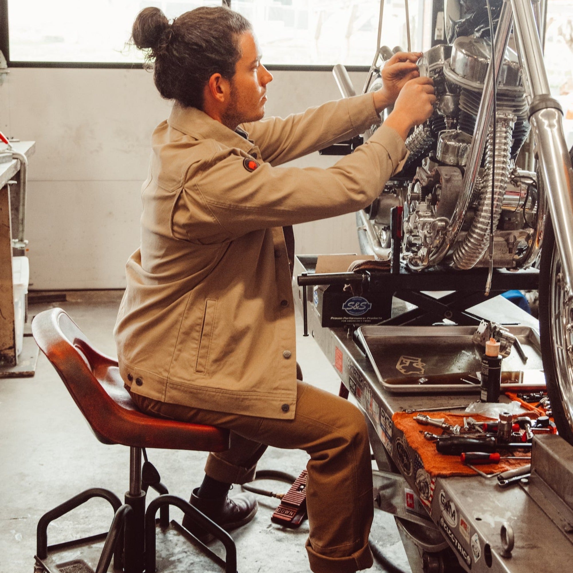 Man wearing Alpine Utility Jacket fixing motocycle