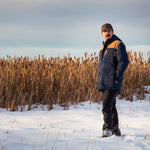 A man wears Pine Peak Down Parka standing in the snow. 