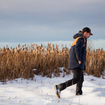 A man wears Pine Peak Down Parka standing in the snow. 