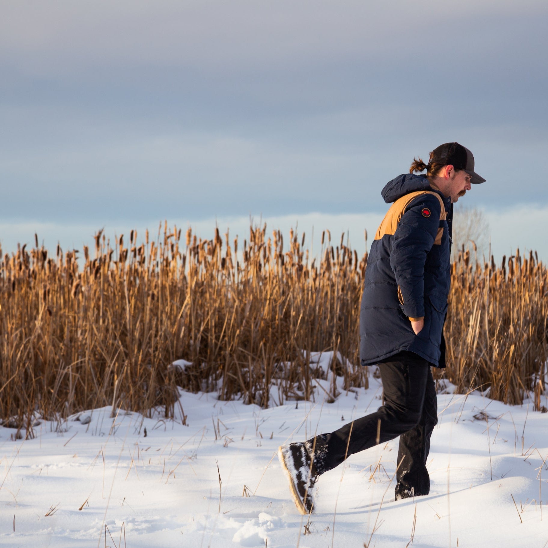 A man wears Pine Peak Down Parka standing in the snow. 