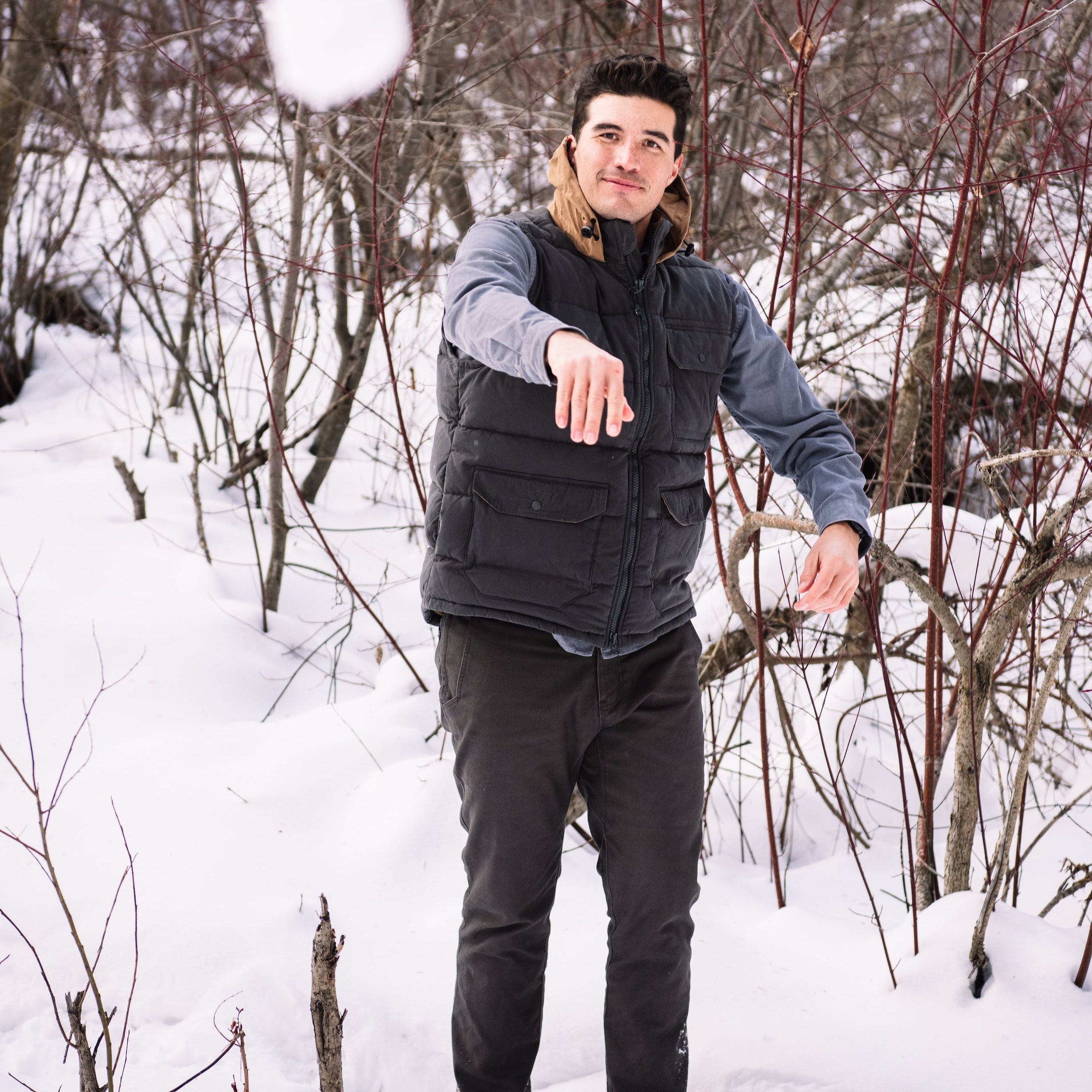 A man wears Pine Peak Down Vest standing in the snow