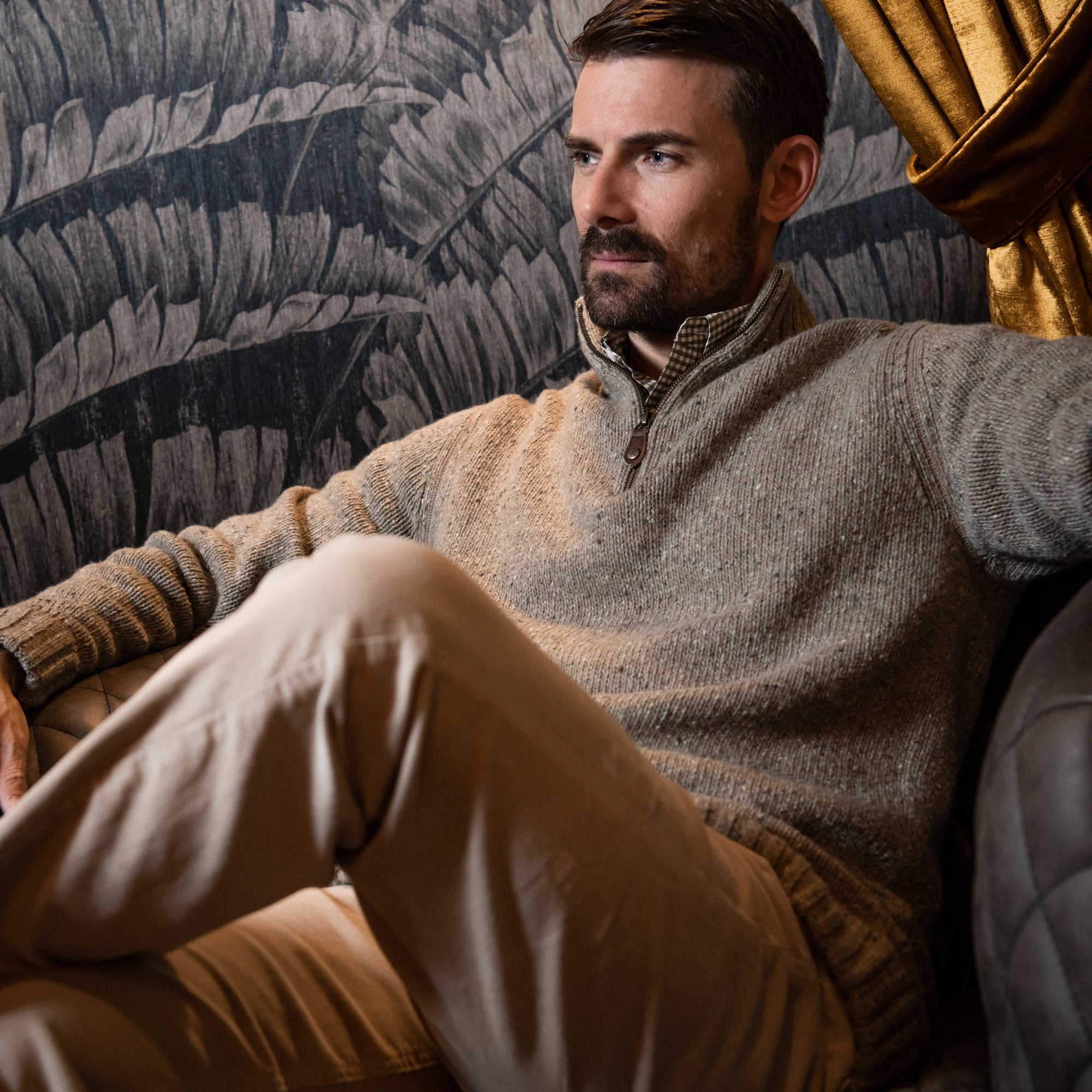 Man wearing Cumberland Donegal Sweater sitting on a sofa