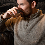 Man wearing Cumberland Donegal Sweater and drinking beverage