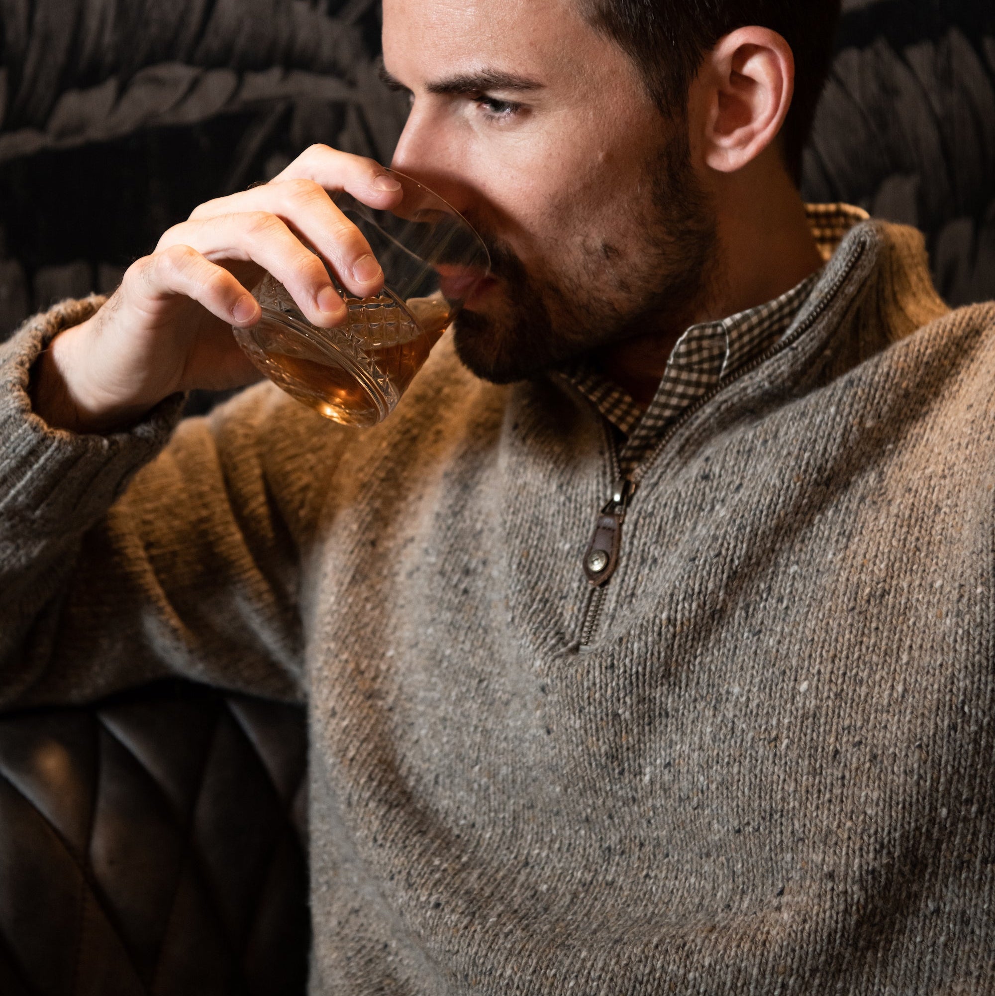 Man wearing Cumberland Donegal Sweater and drinking beverage