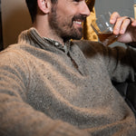 Man wearing Cumberland Donegal Sweater and drinking beverage