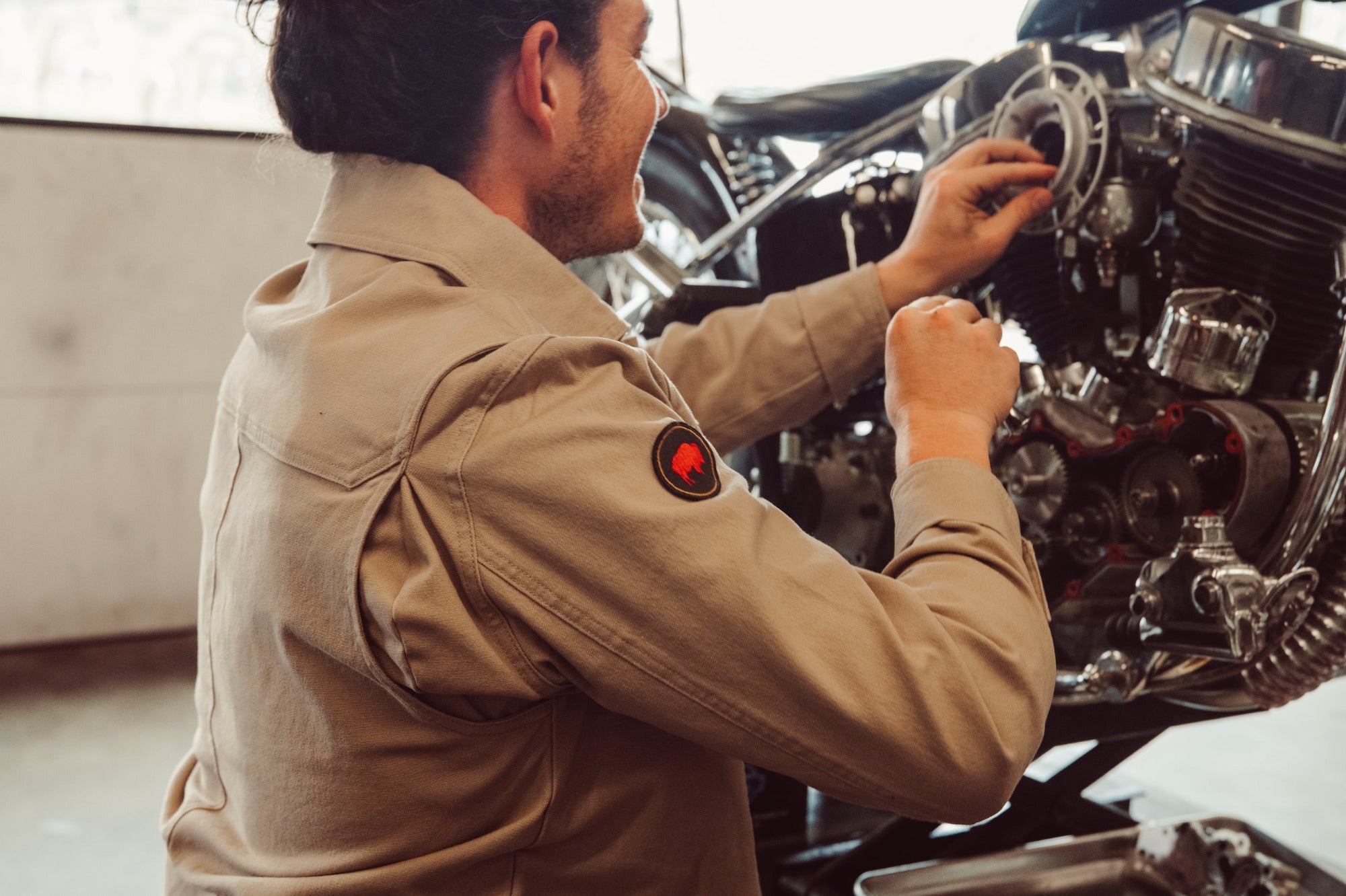 Man weariing Alpine Utility Jacket fixing motorcycle