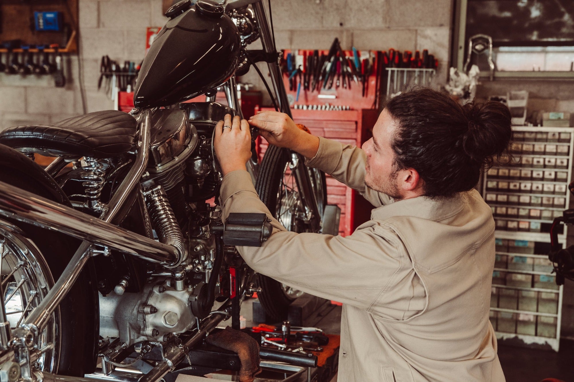 Man wearing Alpine Utility Jacket fixing motorcycle