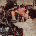 Man wearing Alpine Utility Jacket fixing motorcycle