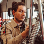 Man wearing Alpine Utility Jacket fixing motorcycle