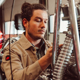 Man wearing Alpine Utility Jacket fixing motorcycle