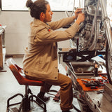Man wearing Alpine Utility Jacket fixing motocycle