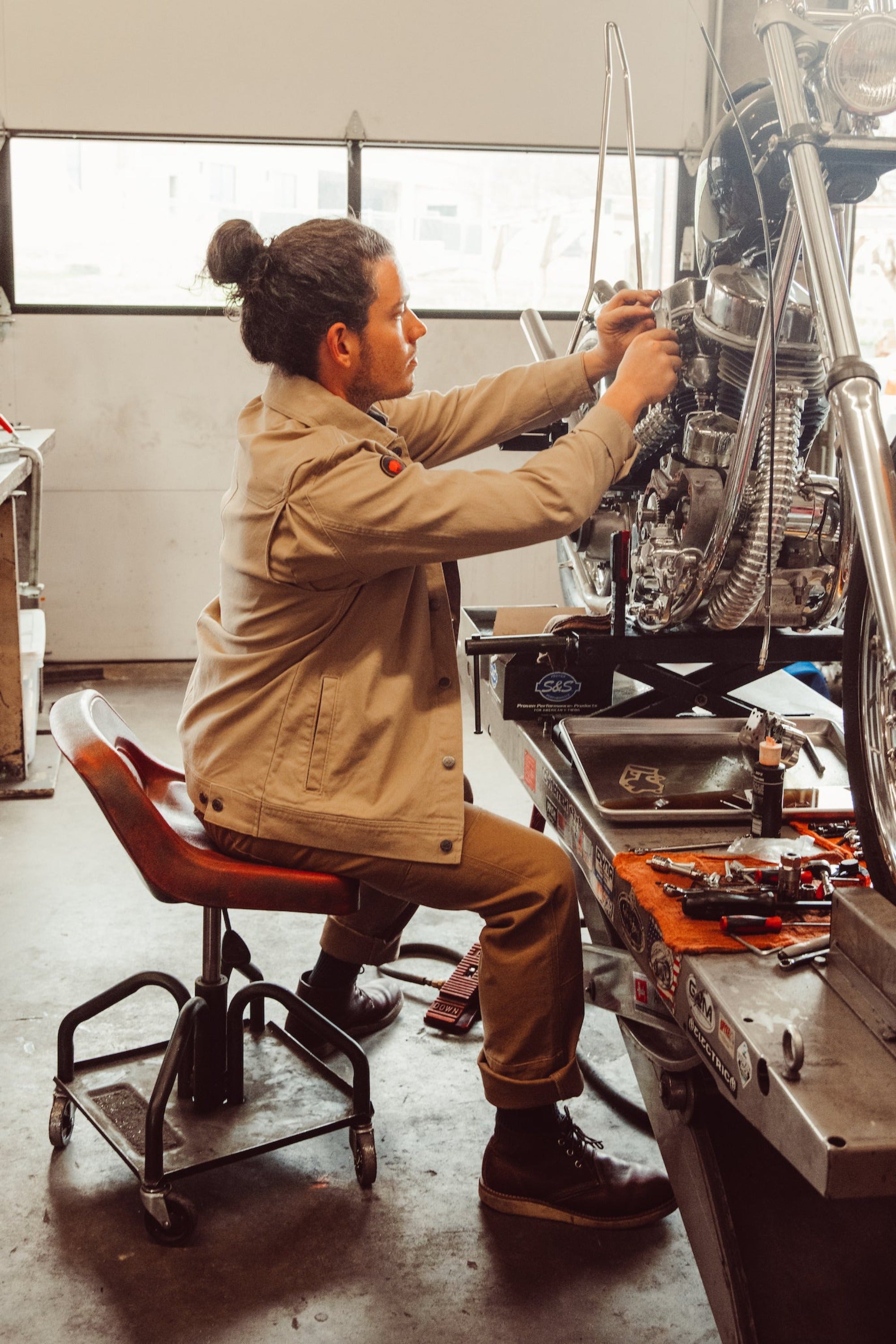 Man wearing Alpine Utility Jacket fixing motocycle